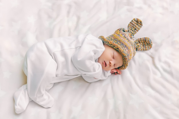 Susses Neugeborenes Baby In Einem Lustigen Hut Mit Hasenohren Schlaft Suss In Einem Kinderbett Auf Einem Weissen Weichen Laken Nahaufnahme Draufsicht Premium Foto