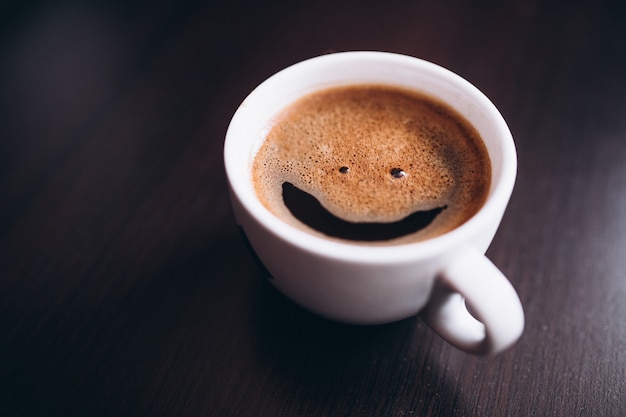 Tasse Kaffee Mit Schaum Lachelngesicht Auf Dem Schreibtisch Lokalisiert Kostenlose Foto