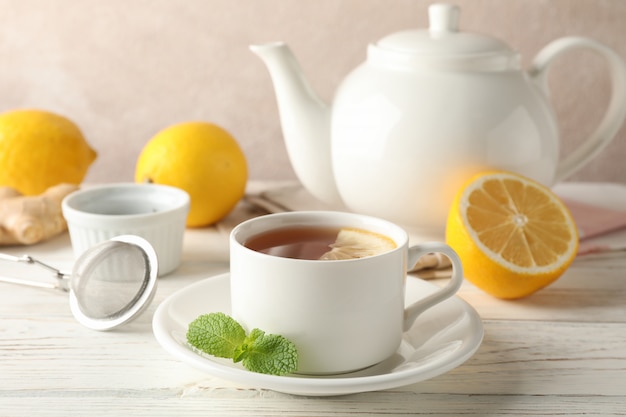 Tasse tee mit zitrone, minze, sieb, ingwer und teekanne auf holz, platz ...