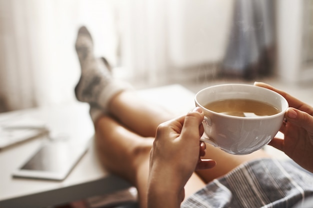 Tasse Tee Und Chill Frau Die Auf Couch Liegt Beine Auf Kaffeetisch Halt Heissen Kaffee Trinkt