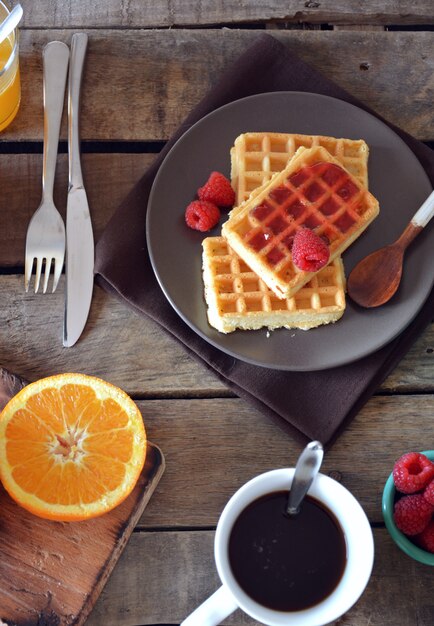 Teller mit waffeln mit himbeermarmelade, orangensaft und kaffee ...