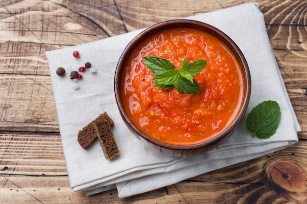 Tomatensuppe in einer hölzernen schüssel mit stücken toast auf einer rustikalen tabelle. Premium Fotos