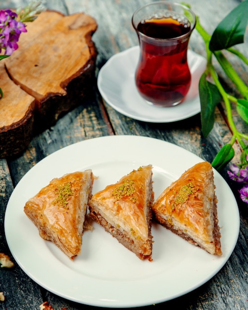 Türkisches baklava mit nüssen und einer tasse heißem tee | Kostenlose Foto