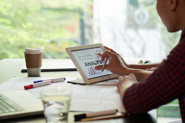 Über der shoukder ansicht der nicht erkennbaren person, die analysediagramm auf tablet-pc überprüft Kostenlose Fotos