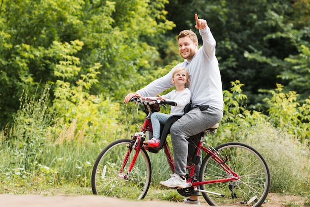 Vater auf dem fahrrad zeigend für tochter Kostenlose Foto