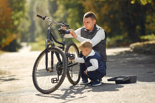 Vater mit sohn reparieren das fahrrad in einem park