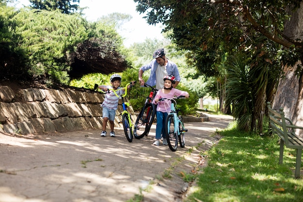 Vater und kinder stehen mit dem fahrrad im park PremiumFoto