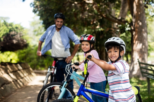 Vater und kinder stehen mit dem fahrrad im park PremiumFoto