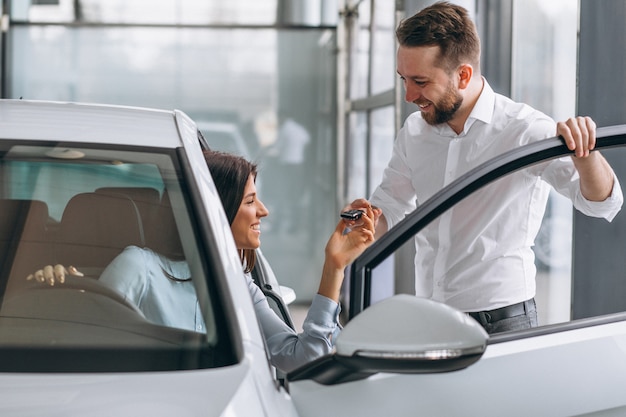 Verkäufer und frau, die nach einem auto in einem autosalon suchen Kostenlose Fotos
