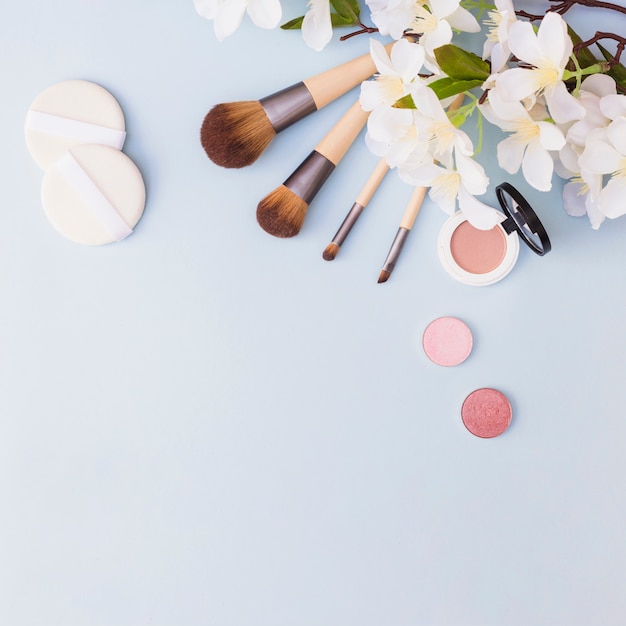 Verschiedene Arten Von Make Up Pinsel Schwamm Lidschatten Und Rouge Mit Weissen Blumen Auf Blauem Hintergrund Kostenlose Foto