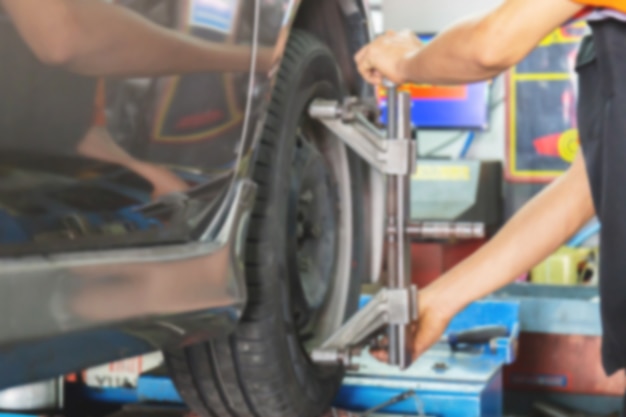 Verschwommen vom mechaniker, der die achsmessvorrichtung auf einem autorad fixiert Premium Fotos