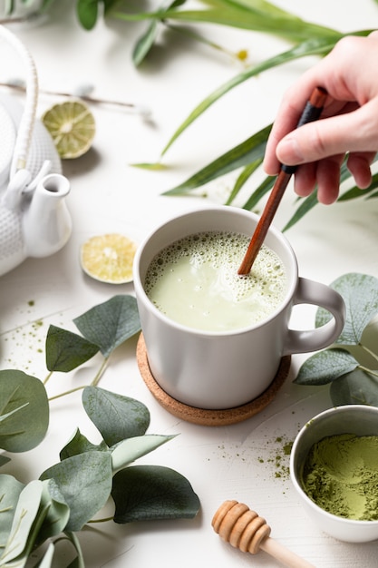 Vertikale aufnahme von grünem tee latte mit milch in einer weißen tasse ...