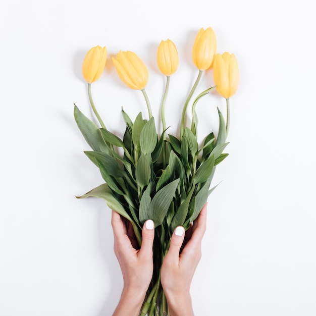 Weibliche hände mit der maniküre, die einen blumenstrauß ...