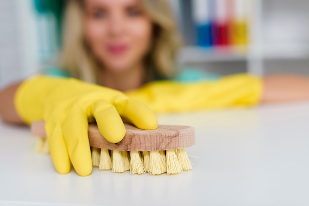 Weibliche hand, die weißen schreibtisch mit hölzerner bürste säubert Kostenlose Fotos