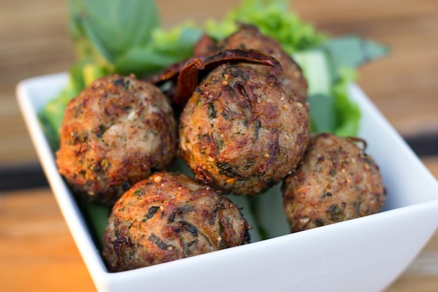 Würzige hackfleischschweinefleischbälle mit salat in einer weißen platte auf dem tisch. thailändisches essen (larb moo tod) Premium Fotos