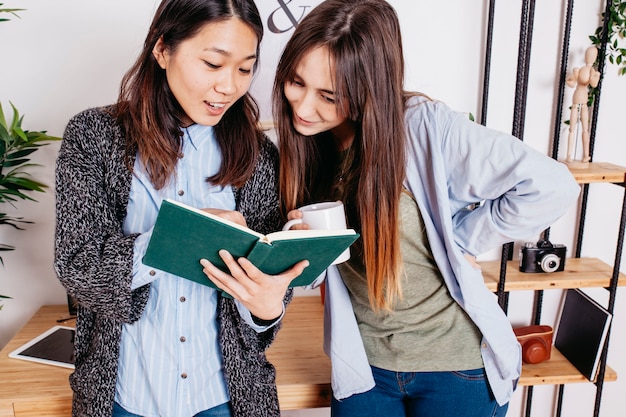 Zufriedene frauen, die interessantes buch erforschen | Kostenlose Foto