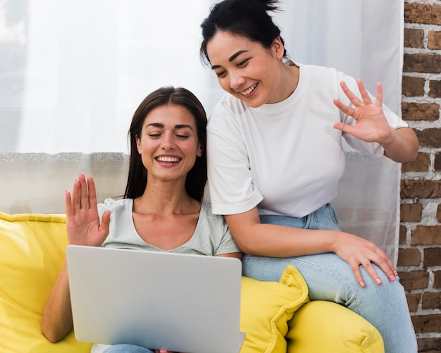 Zwei Frauen Auf Couchvideo Die Sich Unterhalten Und Am Laptop Winken Kostenlose Foto