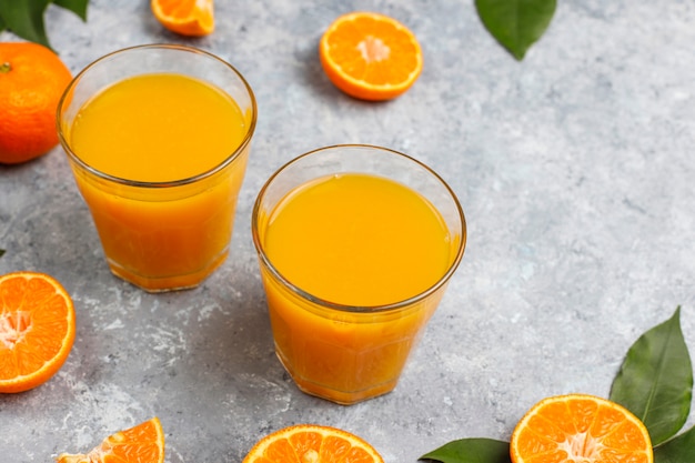 Zwei gläser organischer frischer orangensaft mit rohen orangen ...