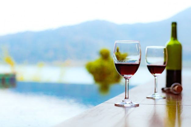 Zwei gläser rotwein in der nähe des swimmingpools mit einem spektakulären blick auf das meer Premium Fotos