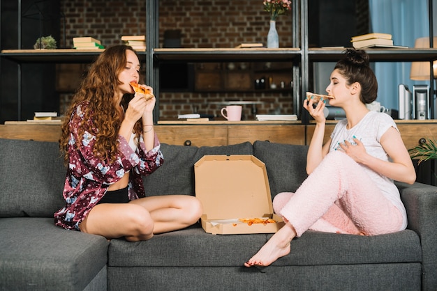 Zwei Junge Frauen Die Auf Dem Sofa Isst Pizza Sitzen Premium Foto 