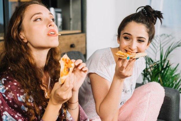 Zwei junge frauen, die zu hause pizza essen | Kostenlose Foto