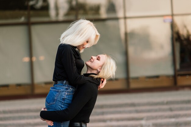 Zwei Junge Frauen Gehen Lächelnd Umarmen Und Küssen Im Freien In Der Stadt Premium Foto 