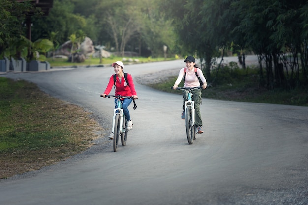 Zwei stilvolle junge freundinnen auf einem fahrrad entlang