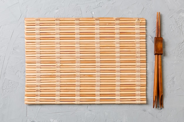 Zwei sushi-stäbchen mit leerer bambusmatte oder holzplatte Premium Fotos