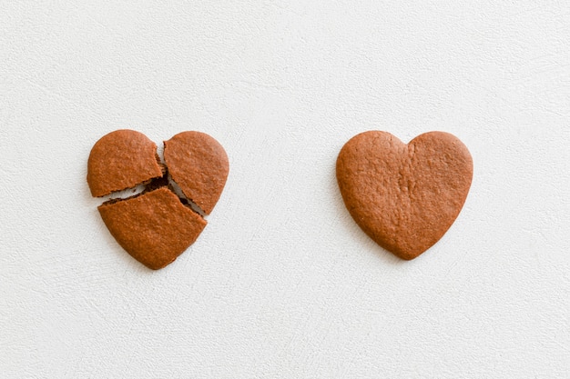 2つのハート型のクッキー そのうちの1つは白い背景に壊れています ハート型のcookieをクラックして 関係を破壊し 終了する概念 片思いを愛します 報われない愛の概念 Valenti プレミアム写真