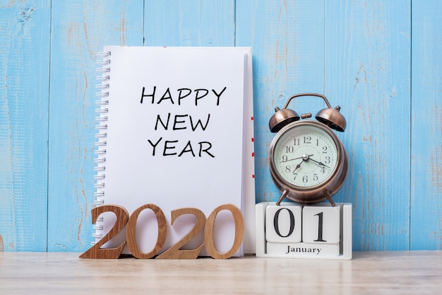 2020 happy new year  with notebook, retro alarm clock and wooden number. Premium Photo