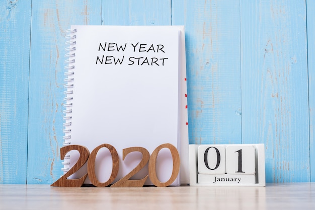 2020 new year new start word on notebook and wooden number. Premium Photo
