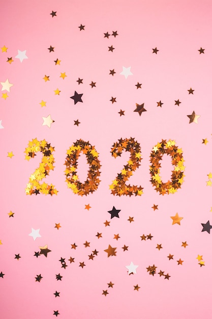 Premium Photo | 2020 new year symbol of gold confetti on pink background.