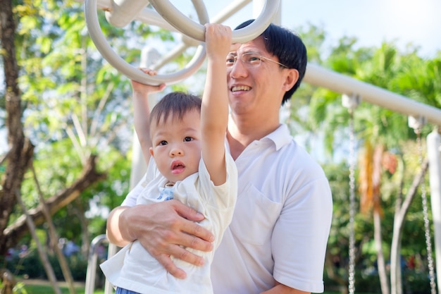 若い父親とかわいい小さなアジア2歳の幼児男の子子供屋外で楽しんで運動し パパが追いつくのに役立ちます プレミアム写真