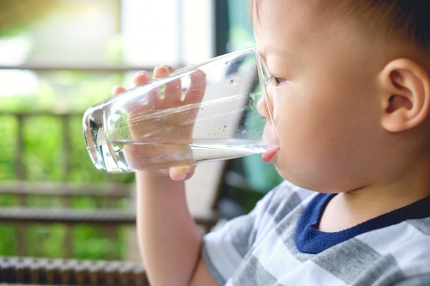 かわいいのどが渇いて少しアジア2歳幼児男の子子供保持し 水のガラスを飲む プレミアム写真