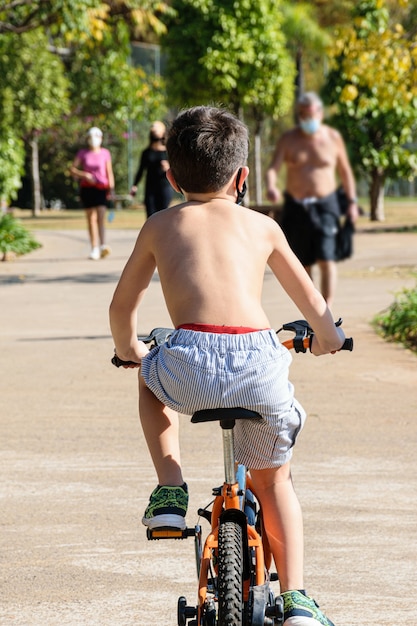 晴れた日に公共の公園で自転車に乗って、上半身裸の8歳の子供 