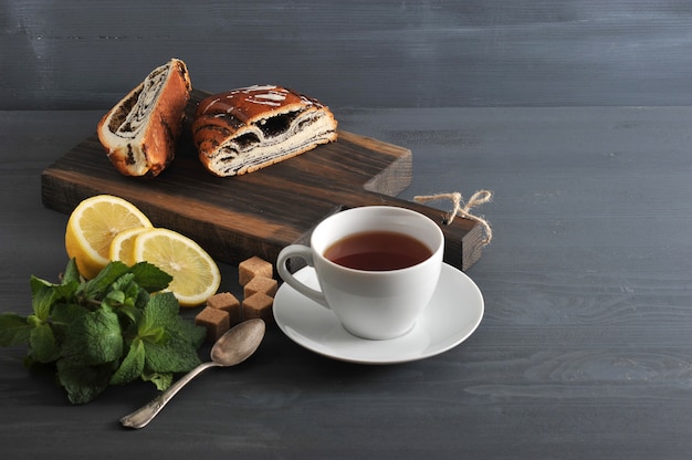 木製の表面にケシの実、紅茶、レモン、ミントを巻きます Premium写真
