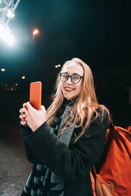 Блондинка с смартфон ночью на улице. Бесплатные Фотографии