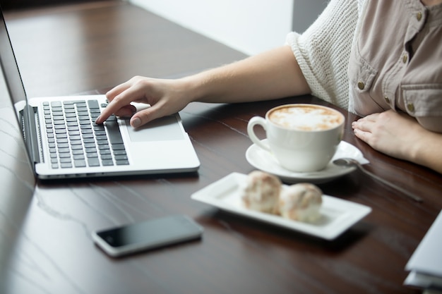 カフェ、ノートパソコンで働く女性の手のクローズアップ | 無料の写真