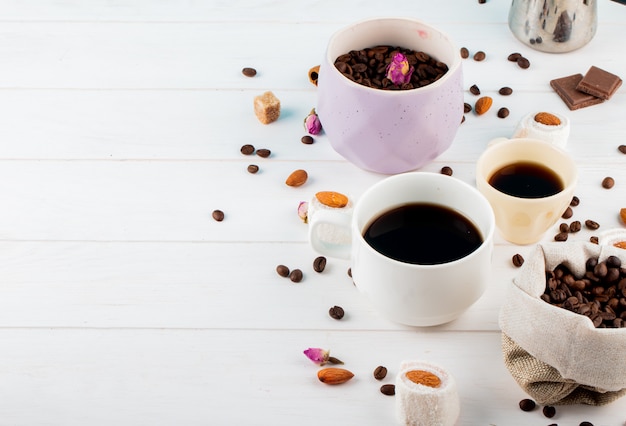 ボウルにコーヒー豆とコピースペースと白い背景の上のコーヒーカップの側面図 無料の写真