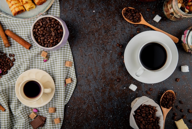 コピースペースと黒の背景のコーヒー豆とコーヒーカップのトップビュー 無料の写真