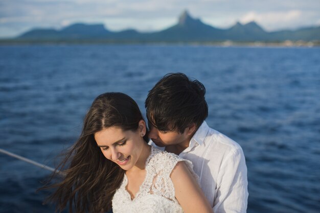 美しい結婚式のカップルの海で屋外の結婚式の日にヨットの上で新郎新婦 幸せな結婚カップルが海でボートにキスします プレミアム写真