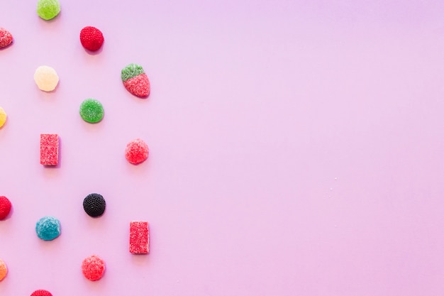 ピンクの壁紙に様々なカラフルなゼリー砂糖キャンデー 無料の写真