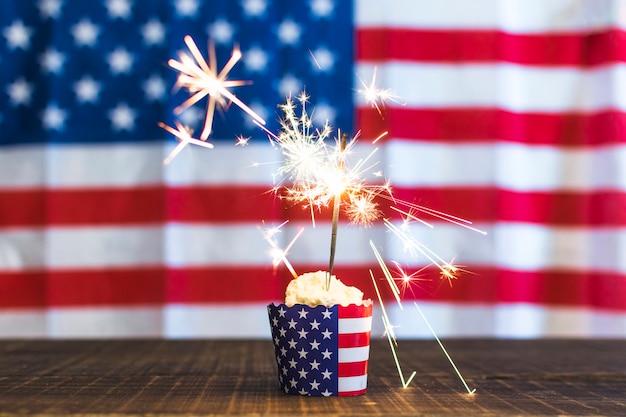 多重アメリカ国旗背景に対してカップケーキに線香花火を燃焼 無料の写真