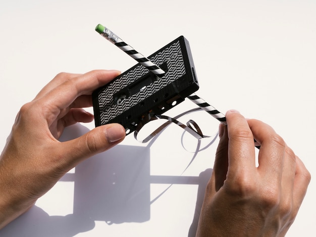 鉛筆で黒いカセットテープを修理する人 無料の写真