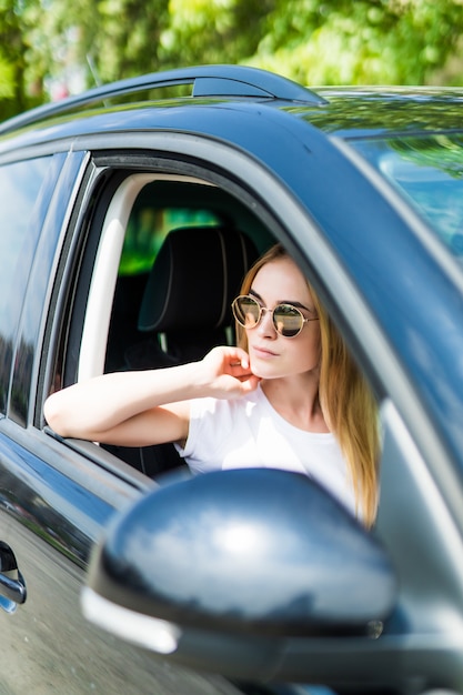 彼女の車を運転してサングラスで美しい若い女性 無料の写真