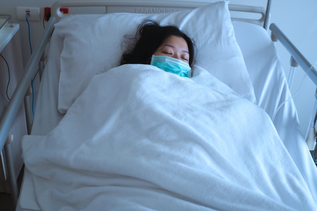 病気を回復するために病院のベッドで寝ているアジアの女性患者 プレミアム写真