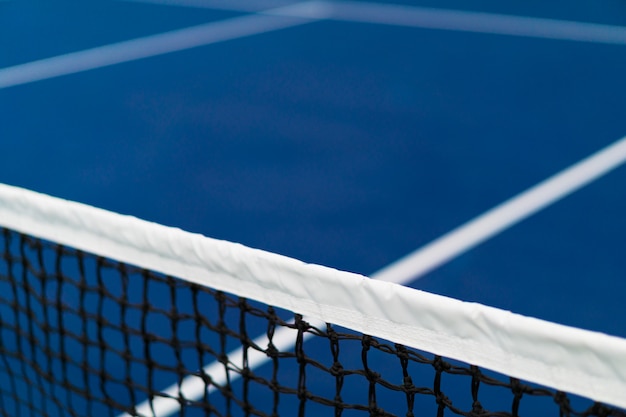 青いハードコート テニス競争の概念に白いストライプとテニスの斜めネット プレミアム写真