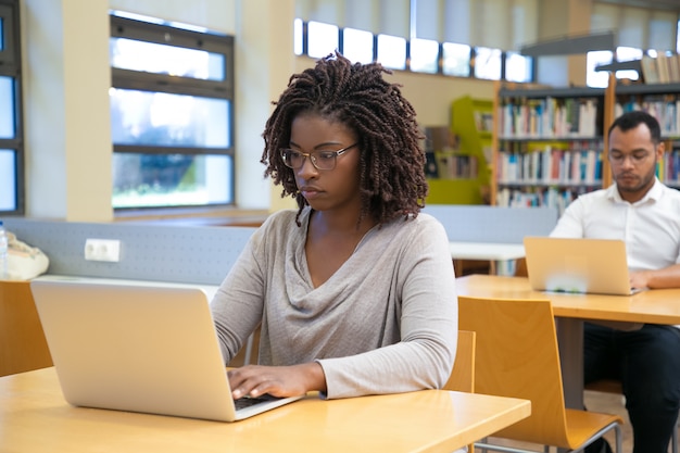 図書館でノートパソコンを扱う若い女性を集中 無料の写真