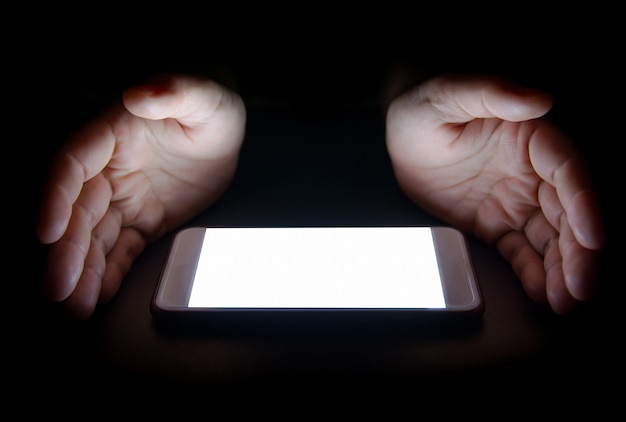 スマートフォンからの白色光は、暗闇の中で夜にあなたの手を反射します