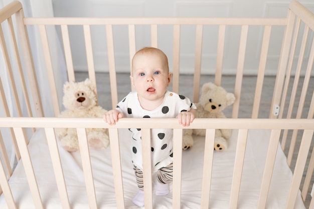 8ヶ月の赤ちゃんが寝た後 明るい子供部屋のパジャマのおもちゃでベビーベッドに立って カメラ 上面図 テキストの場所を見る プレミアム写真